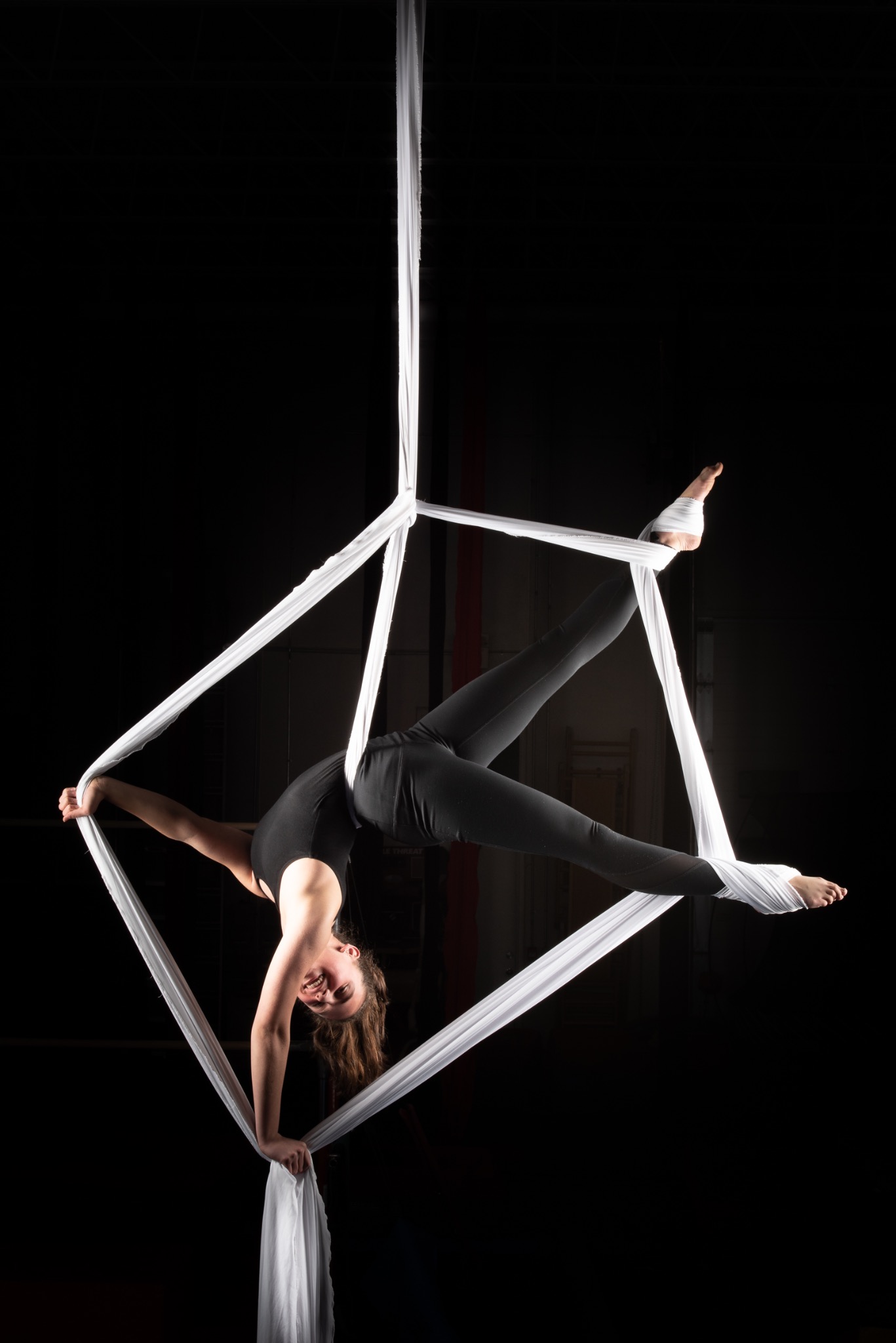 Prestige aerial performer demonstrating a white silks pose